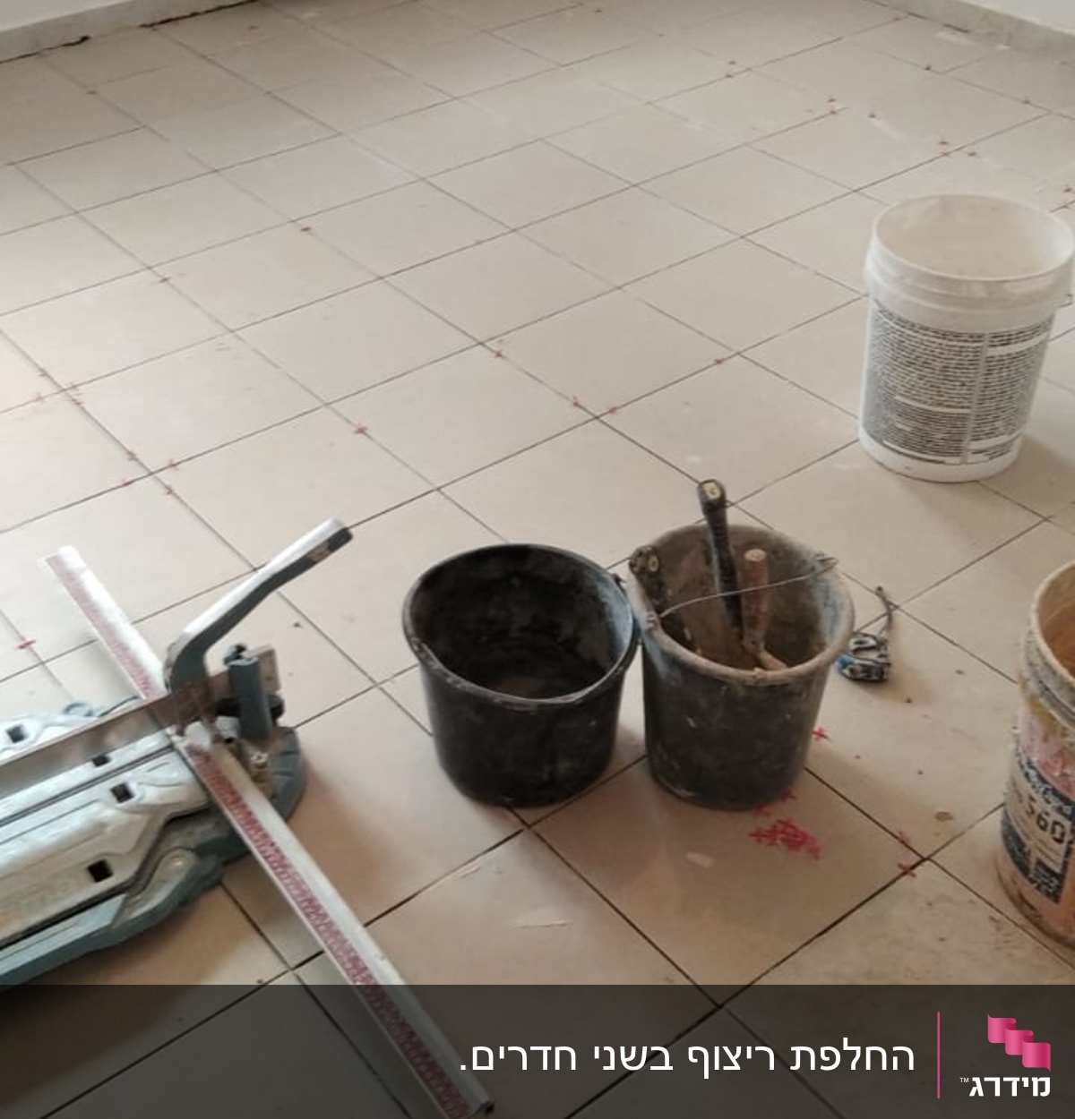 כלי עבודה לריצוף, דלי וחומרי בנייה על רצפה